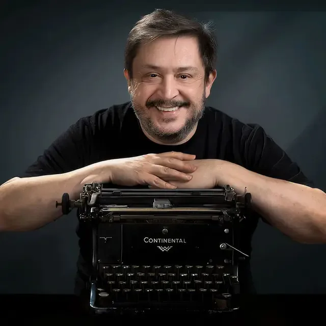Hernán Casciari sonríe apoyado sobre una máquina de escribir Continental.